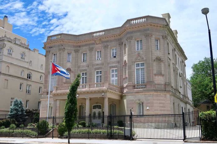 neoclassical stone building with a Cuban flag and iron fence