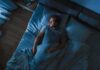 Man lying in bed at night looking toward window