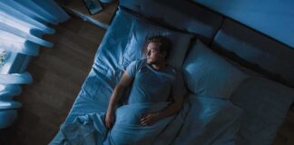 Man lying in bed at night looking toward window