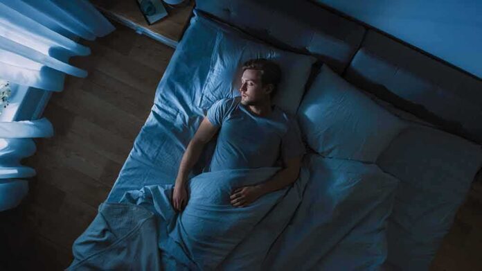 Man lying in bed at night looking toward window