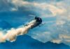 Helicopter releasing smoke over mountains