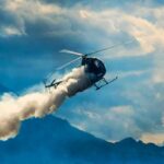 Helicopter releasing smoke over mountains