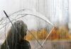person with clear umbrella seen through a rainy window