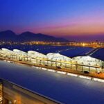 Airport terminal at dusk with illuminated wave-like roof