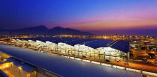 Airport terminal at dusk with illuminated wave-like roof