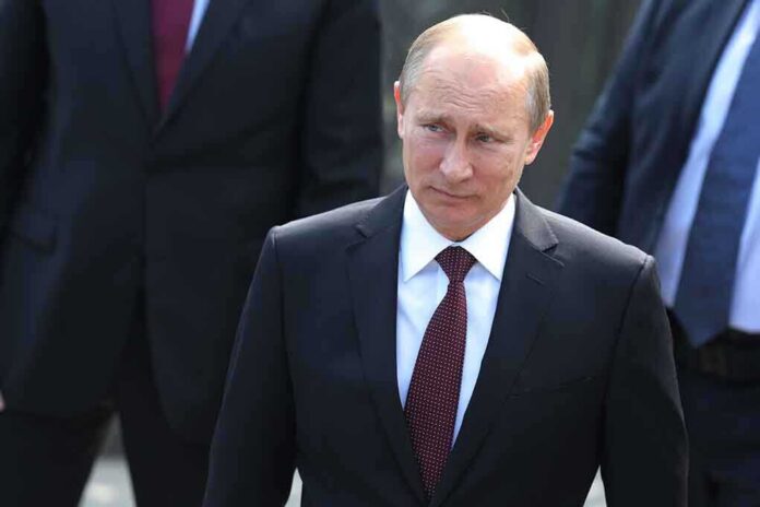 Vladimir Putin in a dark suit with a red tie walking outdoors