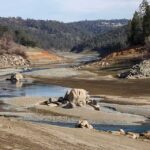 Drought-exposed riverbed with scattered boulders and low water