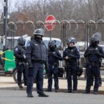 Five Arrests Put A Key Airbase On Alert Group of police officers in riot gear standing on a street; Brian Folkerts present
