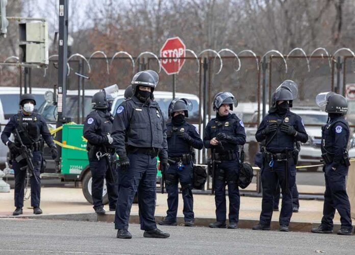 shutterstock_1898881783 Group of police officers in riot gear standing on a street; Brian Folkerts present