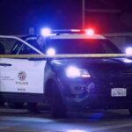 Police SUV with flashing lights at night behind yellow tape