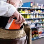 A New York Shoplifting Argument Is Turning Heads Hand placing a box into a shoulder bag in a store aisle