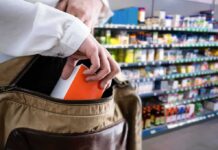 Hand placing a box into a shoulder bag in a store aisle