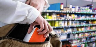 Hand placing a box into a shoulder bag in a store aisle