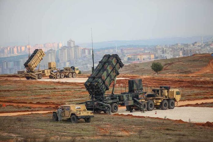 Patriot missile launchers deployed on a field near a city