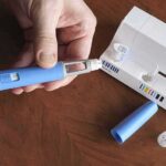 Hands assembling a blue insulin pen with packaging on a table