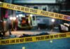 police tape cordons off a dimly lit crime scene alley