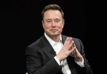 Man in a dark suit with hands clasped together
