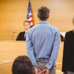 One Deleted Message Pointed Somewhere Very Dark Defendant in handcuffs standing before a judge in a courtroom