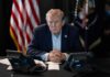 Donald Trump seated at a table between two desk phones