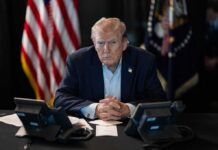 Donald Trump seated at a table between two desk phones