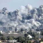Massive smoke plumes rise over a city after explosions