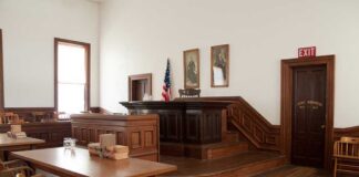 Interior of a historic courtroom with wooden furniture and an American flag