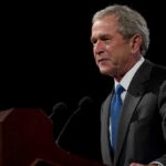 George W. Bush speaking at a podium with microphones