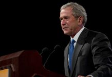 George W. Bush speaking at a podium with microphones