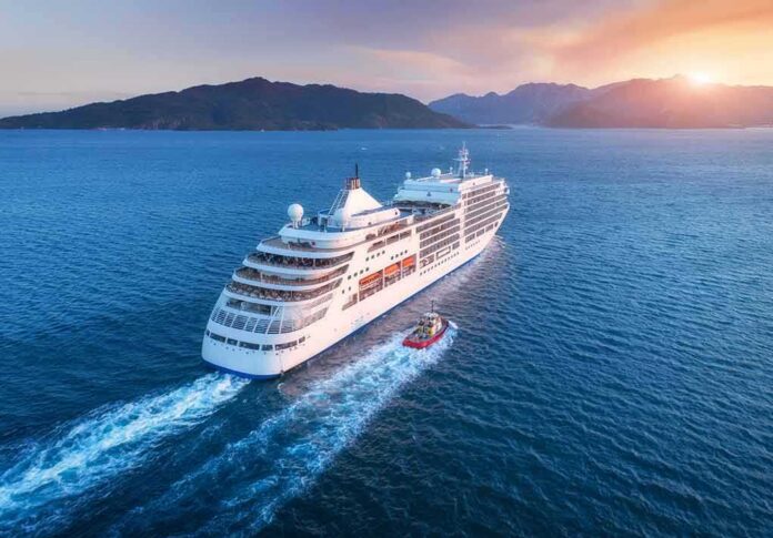 Cruise ship sailing at sunset near mountainous coast