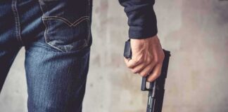 person holding a handgun by their side