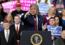 Port Huron Eruption – ‘Paid’ Heckler Ousted Donald Trump speaking at a rally podium, pointing toward the audience