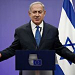 A Forgotten Two-State Speech Is Back Again man in suit speaking at a podium with Israeli flag