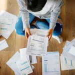 The Midterms Are Becoming a Battle Over Bills Person sitting on floor sorting bills and invoices