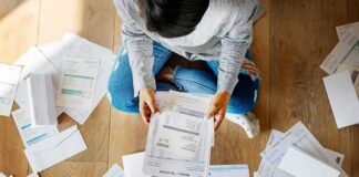 Person sitting on floor sorting bills and invoices