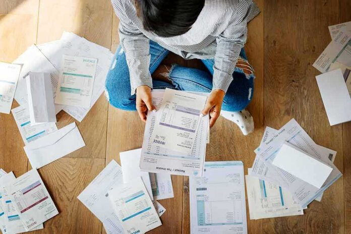 Person sitting on floor sorting bills and invoices