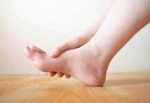 Innocent Sprain? Cancer Was Hiding Hand holding the arch of a bare foot on a wooden floor