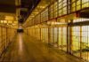 Prison cell block corridor with barred cells and upper walkways