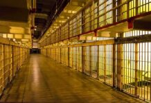 Prison cell block corridor with barred cells and upper walkways