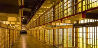 Prison cell block corridor with barred cells and upper walkways