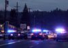 Police cars with flashing lights block a road at night