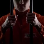Public Execution Shocks America – Pentagon Greenlights Prisoner in orange jumpsuit gripping jail bars