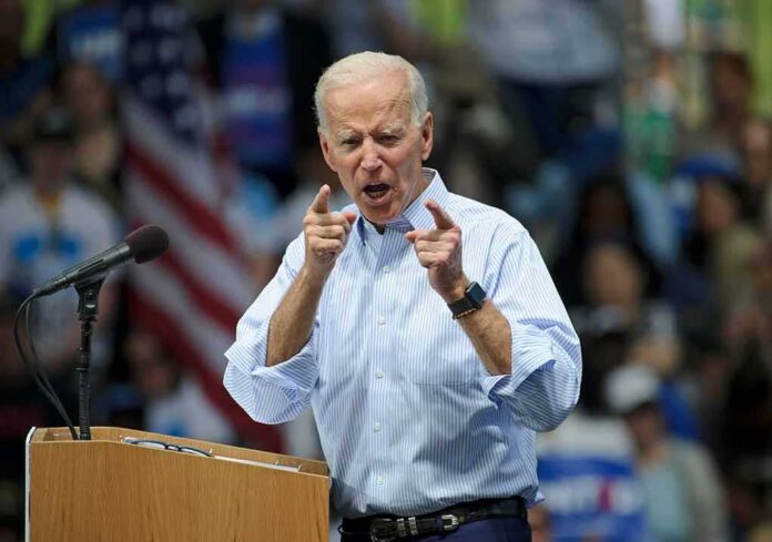 Joe Biden speaking at a rally, pointing with both hands at the podium