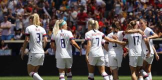 Alex Morgan, Crystal Dunn, Christian Jones, and Walter Jones among teammates celebrating on a soccer field