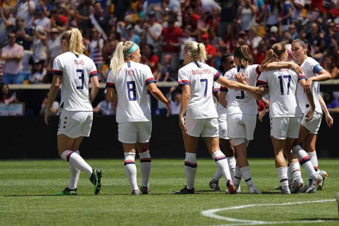 shutterstock_1419232265 Alex Morgan, Crystal Dunn, Christian Jones, and Walter Jones among teammates celebrating on a soccer field