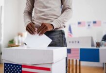 Voter places ballot into a box at a polling station