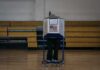 Voter at a polling booth in a gymnasium