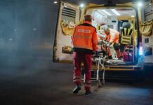 Paramedics load a patient into an ambulance at night
