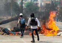 Protesters near a burning barricade on a city street