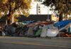 Street encampment with tarps and makeshift tents by roadside