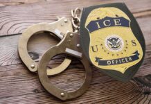 ICE officer badge and handcuffs on wooden surface